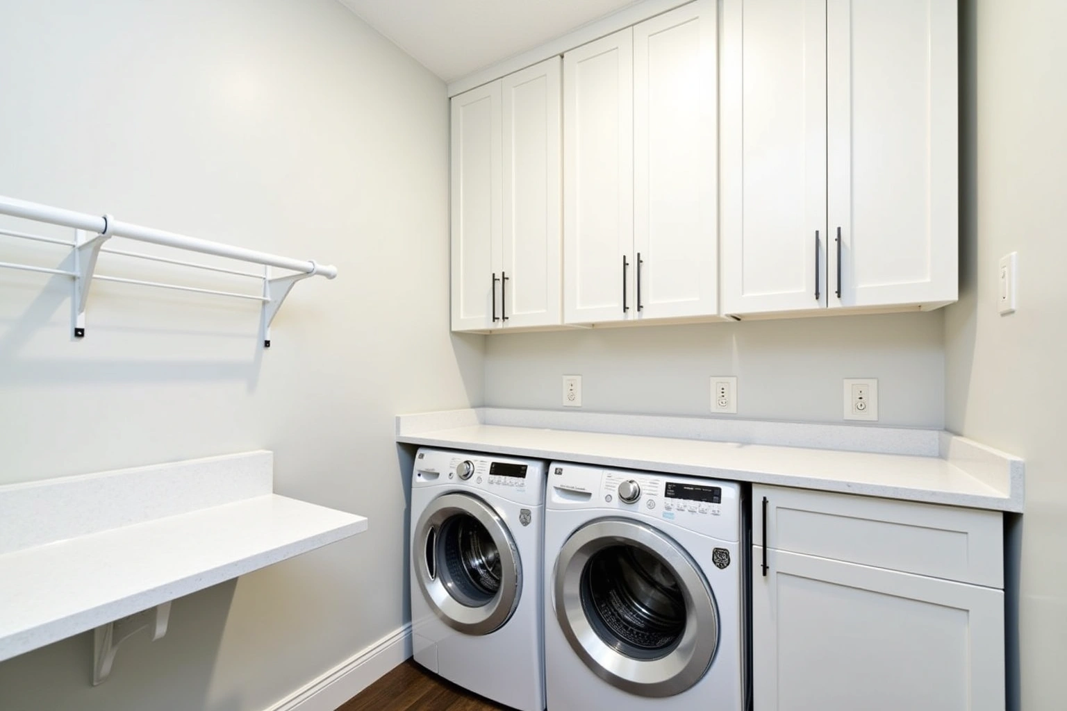 Laundry room with white shaker upper cabinets over a front-loading washer and dryer under a white quartz folding counter.
